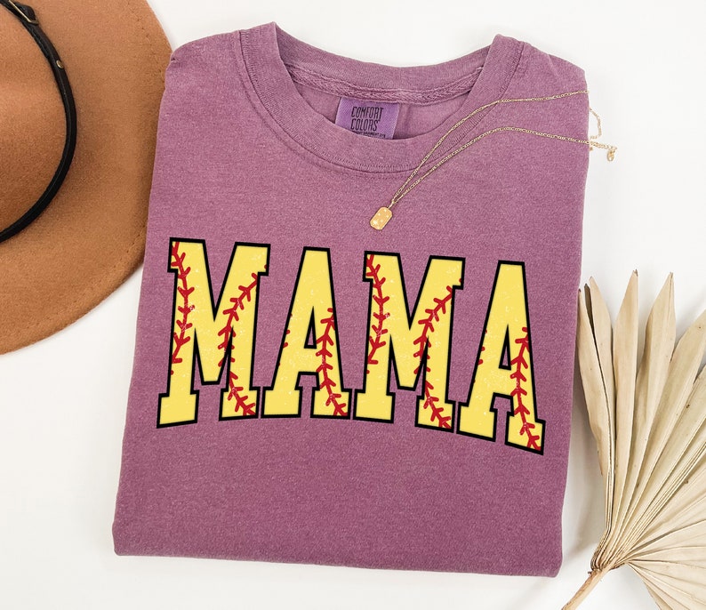 May include: Purple t-shirt with the word "MAMA" in yellow letters with red stitching, resembling a softball.