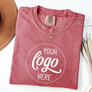 May include: A red t-shirt with a white circle that says "YOUR logo HERE" in a cursive font.