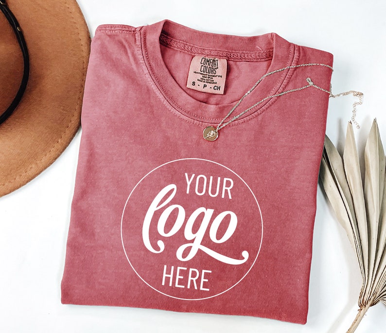 May include: A red t-shirt with a white circle that says "YOUR logo HERE" in a cursive font.