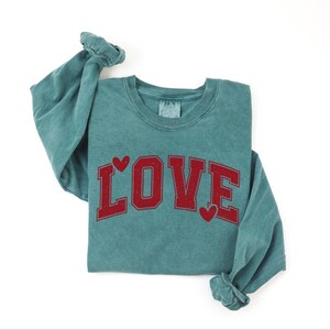 A green long-sleeved shirt with the word "LOVE" printed in red letters.