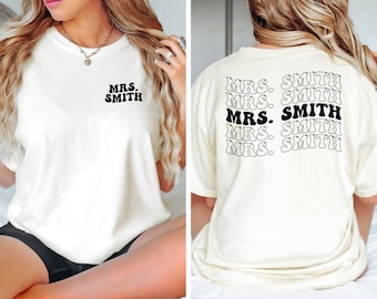 May include: White t-shirt with "MRS. SMITH" printed on the front and back in a retro font. The text is repeated five times on the back.