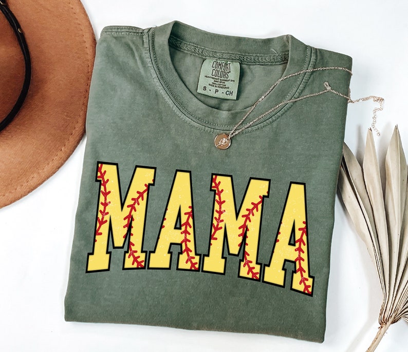May include: A green t-shirt with the word "MAMA" in yellow letters with a red baseball stitch design.