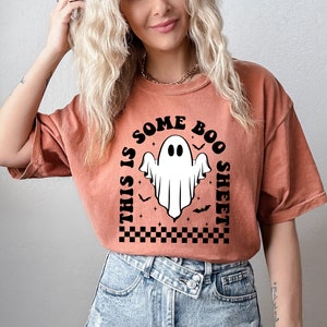 以下が含まれることがあります： 黒と白の幽霊のグラフィックが描かれた、焦げ茶色のTシャツ。テキストは「This is some boo sheet」です。