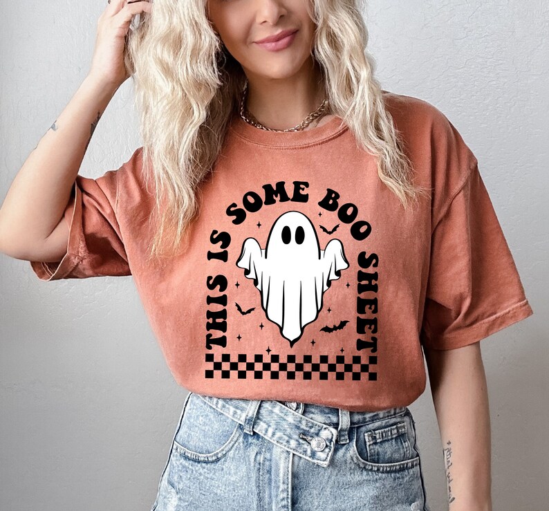 以下が含まれることがあります： 黒と白の幽霊のグラフィックが描かれた、焦げ茶色のTシャツ。テキストは「This is some boo sheet」です。