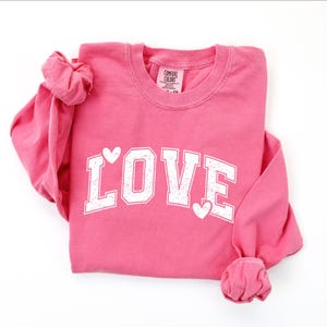 A pink long-sleeved shirt with the word "LOVE" printed in white letters.