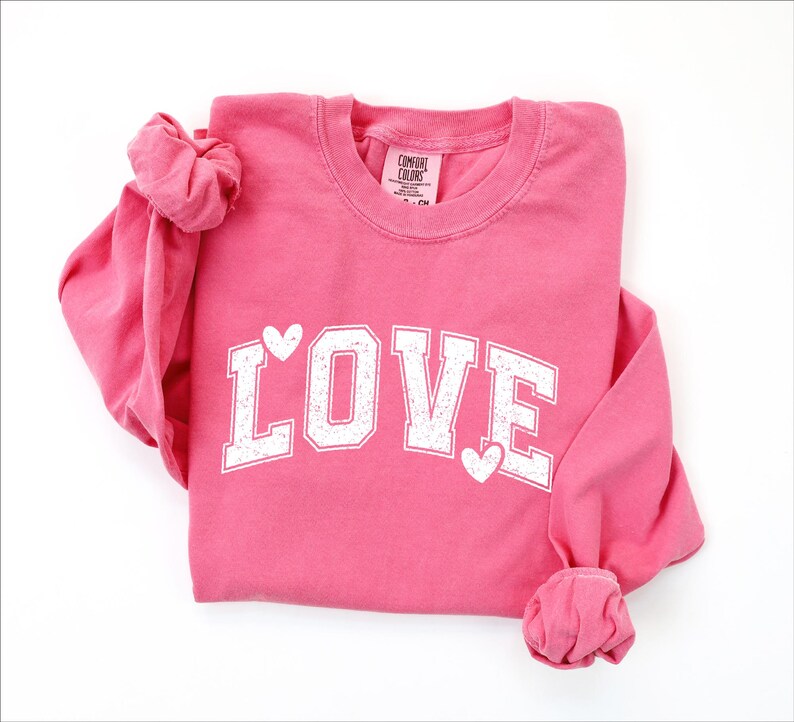 A pink long-sleeved shirt with the word "LOVE" printed in white letters.