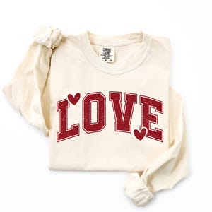 A white long-sleeved t-shirt with the word "LOVE" printed in red letters.