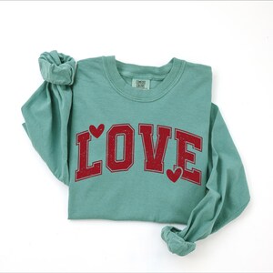 A green long-sleeved t-shirt with the word "LOVE" printed in red letters.