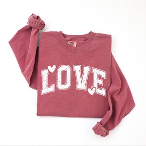 A red long-sleeved t-shirt with the word "LOVE" printed in white letters.
