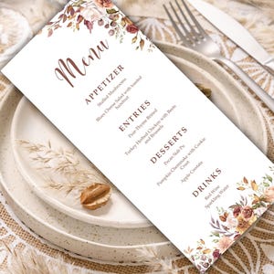 Könnte beinhalten: Eine rechteckige weiße Menükarte mit braunem Text und Blumenillustrationen in Rost-, Creme- und Brauntönen. Das Menü enthält Abschnitte für Appetizer, Entries, Desserts und Drinks mit den entsprechenden Speisen und Getränken.