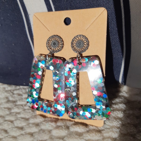 Boucles d'oreilles en résine forme géométrique et teintées de grosses paillettes multicolores. Bijou artisanal fait mains pour femme