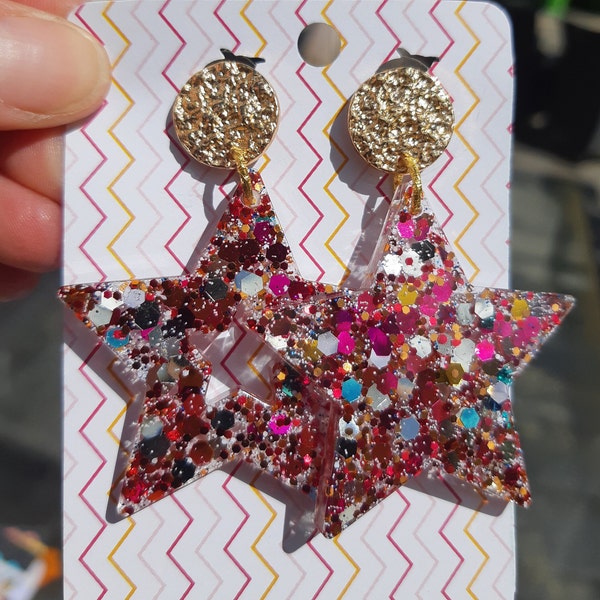 Boucles d'oreilles en résine de forme étoile et teintées de paillettes multicolores. Bijou artisanal pour femme, cadeau fait mains pour elle