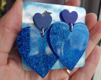 Heart-shaped resin earrings tinted with blue glitter. Handcrafted jewelry for women, handmade gift for her