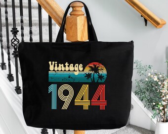 May include: Black tote bag with a vintage 1944 design featuring a sunset and palm trees. The text "Vintage 1944" is printed in a retro font.