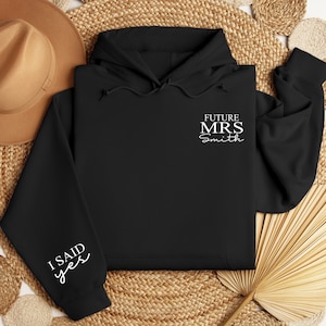 May include: Black hoodie with white text that says "Future Mrs. Smith" on the front and "I said yes" on the sleeve.