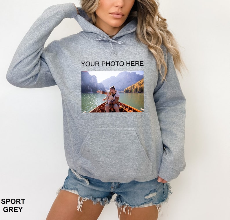 May include: A gray hooded sweatshirt with a pocket on the front. The sweatshirt has a photo of a couple on a boat on a lake printed on the front. The text "YOUR PHOTO HERE" is printed above the photo.