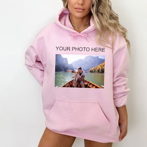 May include: Pink hoodie with a pocket and a photo of two people in a boat on a lake. The text "YOUR PHOTO HERE" is printed above the photo.