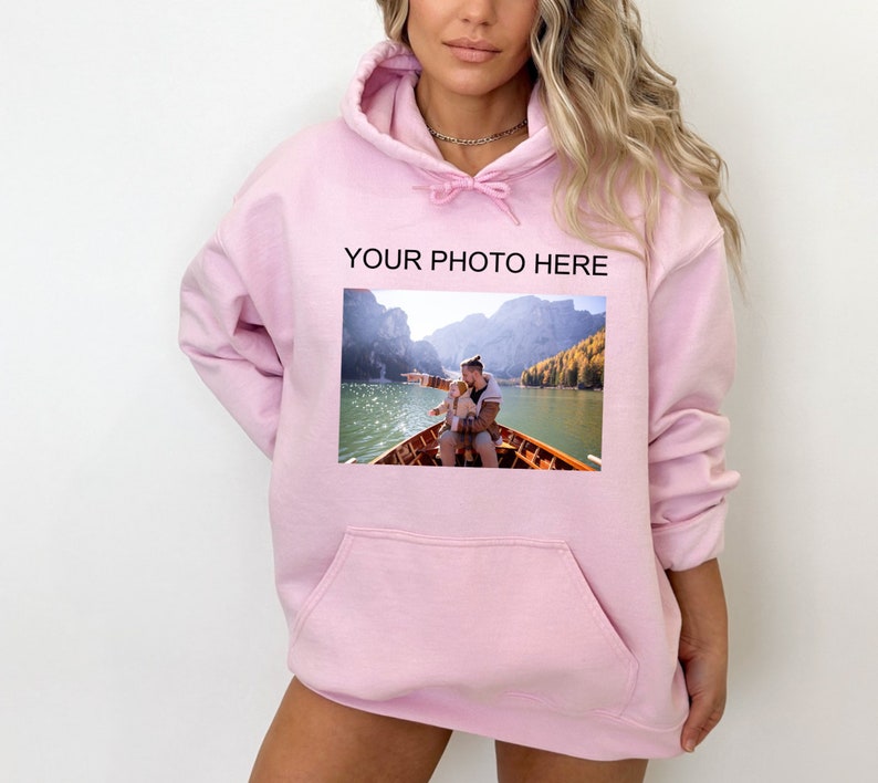May include: Pink hoodie with a pocket and a photo of two people in a boat on a lake. The text "YOUR PHOTO HERE" is printed above the photo.