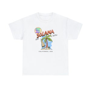 Op de afbeelding: Wit T-shirt met een grafisch ontwerp van een palmboom op een eiland met de tekst "Solana Est. 2020 Californië, USA"