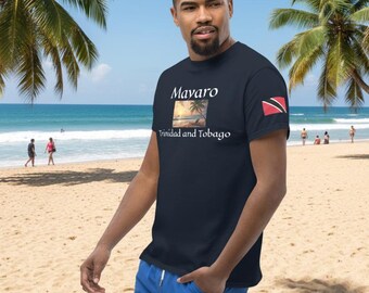 May include: Navy blue t-shirt with the text "Mavaro" above a beach scene and "Trinidad and Tobago" below. A Trinidad and Tobago flag is on the left sleeve. The person is wearing blue shorts and standing on a sandy beach.