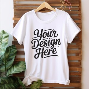 K&ouml;nnte beinhalten: Wei&szlig;es T-Shirt mit dem Text "Your Design Here" in einer schwarzen, stilisierten Schrift.
