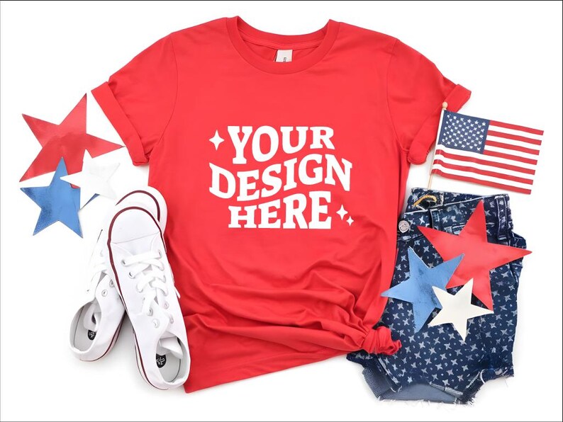 May include: A red t-shirt with the text "YOUR DESIGN HERE" in white, paired with denim shorts, white sneakers, and star-shaped decorations in red, white, and blue. An American flag is also included.