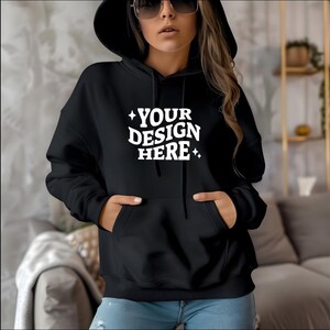 Pu&ograve; includere: Felpa con cappuccio nera con il testo "YOUR DESIGN HERE" in lettere bianche con due piccole stelle su entrambi i lati del testo.
