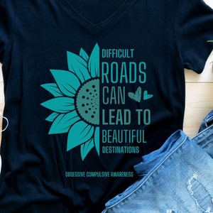 May include: Black t-shirt with a teal sunflower graphic and the text "Difficult roads can lead to beautiful destinations. Obsessive Compulsive Awareness".