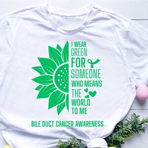 May include: White t-shirt with a green sunflower graphic and the text "I wear green for someone who means the world to me" and "Bile Duct Cancer Awareness".