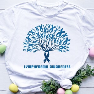 Könnte beinhalten: Weißes T-Shirt mit einem blauen Schleifenbaum-Design und dem Text "Lymphedema Awareness".