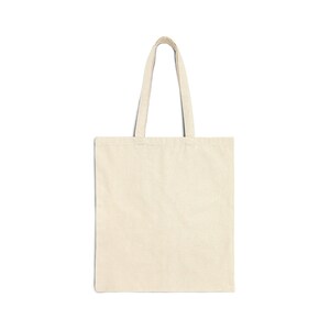 A plain cream canvas tote bag with two handles is displayed flat against a white background.