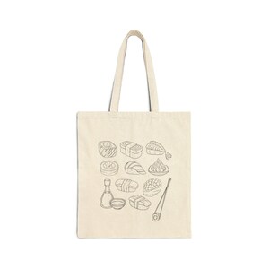 A cream canvas tote bag with a black line art sushi graphic is displayed flat against a white background.