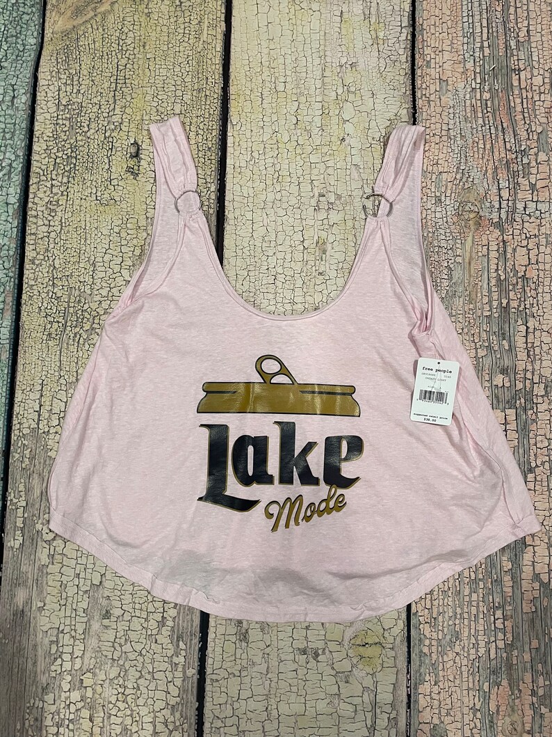 May include: Pink sleeveless tank top with a brown and gold graphic of a can with the text "Lake Mode".