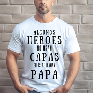 May include: White t-shirt with black text that reads "Algunos heroes no usan capas ellos se llaman papa".