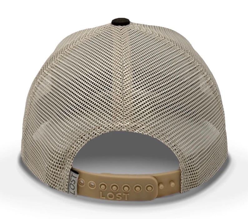 May include: A tan and black trucker hat with a mesh back and a curved brim. The hat has a black button on top and a tan adjustable snap closure. The word "LOST" is printed on the back.