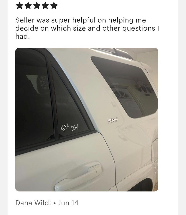 May include: A white vehicle features a small white decal on the rear side window with the letters S.W. and D.W. written in a stylized font. The vehicle body includes a silver SR5 emblem located near the rear window frame and a door handle.