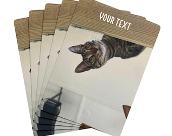 May include: A stack of playing cards featuring a tabby cat looking down. The cards have a wooden border at the top with the text "YOUR TEXT" in white. The cat has brown and black stripes and green eyes.