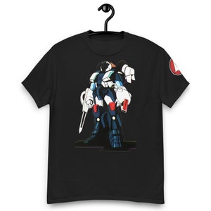 Può includere: Maglietta nera con un'illustrazione di un robot bianco e blu. Il robot tiene un'arma grande nella mano destra e un'arma più piccola nella mano sinistra.