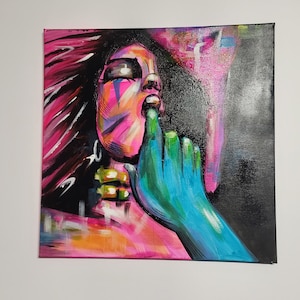 Può includere: Dipinto astratto su tela raffigurante il volto di una donna con un dito sulle labbra. L'opera utilizza colori vivaci tra cui rosa, blu, verde e arancione. Lo sfondo è nero e lo stile è moderno.