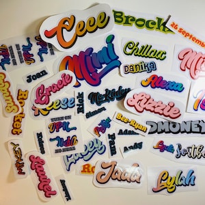 Op de afbeelding: Een verzameling kleurrijke, gepersonaliseerde stickers met namen zoals Ceece, Brock, Mia, Lizzie en Isla. De stickers zijn op een witte achtergrond en hebben een retro, jaren 70-stijl lettertype.