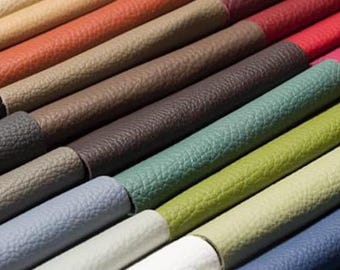 Puede incluir: Primer plano de una colección de muestras de cuero enrolladas en varios colores. Las muestras incluyen tonos de marrón, verde, azul y rojo. El cuero tiene una superficie texturizada y los rollos están dispuestos en diagonal.