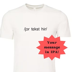 May include: White t-shirt with the text "/jør tekst hir/" printed on the front. A red starburst with the text "Your message in IPA!" is on the right side of the shirt.