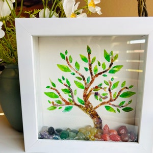 May include: A white framed shadow box with a watercolor painting of a tree made of colorful gemstones. The tree is surrounded by a rainbow of gemstones at the base.