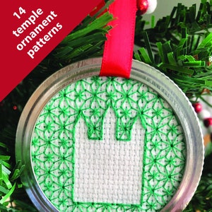 Pode incluir: Um ornamento de Natal bordado em verde e branco com um design de templo. O ornamento é feito de uma tampa de frasco de vidro e está pendurado em uma árvore de Natal verde.