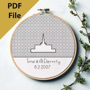 May include: A black and white cross-stitch pattern of a temple with the text "Time & All Eternity 6.2.2007" on a white background in a wooden embroidery hoop.