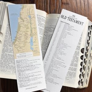 Peut inclure: Livre ouvert avec un marque-page cartographique du Moyen-Orient et un calendrier de lecture de l'Ancien Testament. La carte montre les anciennes régions d'Israël. Le livre est ouvert sur un chapitre avec du texte.