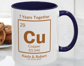 May include: White ceramic mug with a navy blue interior and handle. The mug features the text "7 Years Together" and a copper-themed design with the names "Kayla & Robert" and the date "01.01.2019".