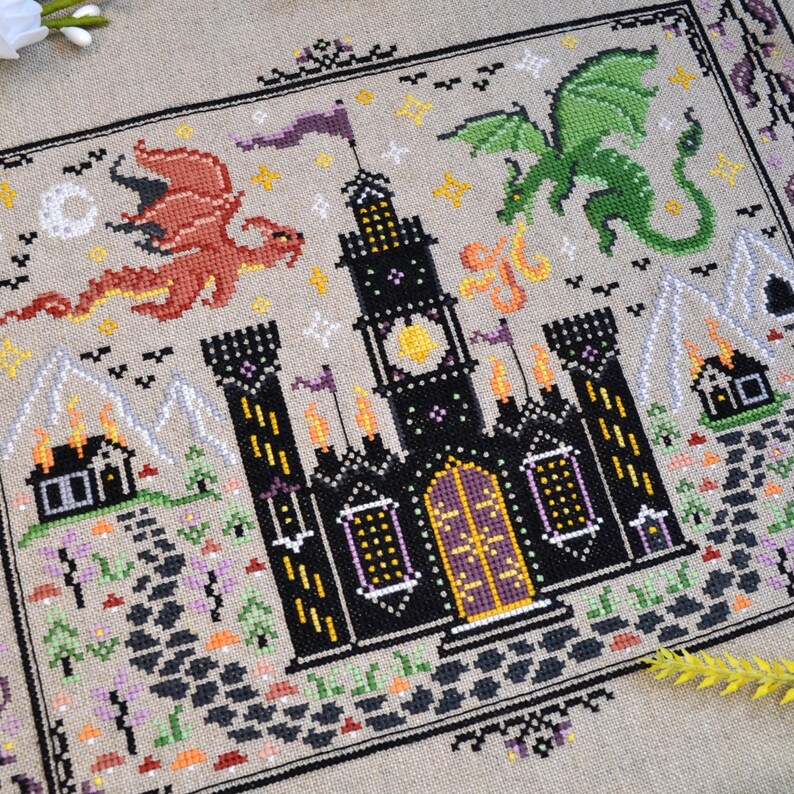 Castles & Dragons cross stitch pattern finish. Features flying fire dragon and a large castle on a scroll.