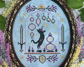 May include: A cross-stitch embroidery featuring a black cat with a crown, surrounded by glowing orbs and candles. The design is set against a light blue background with a gold frame.