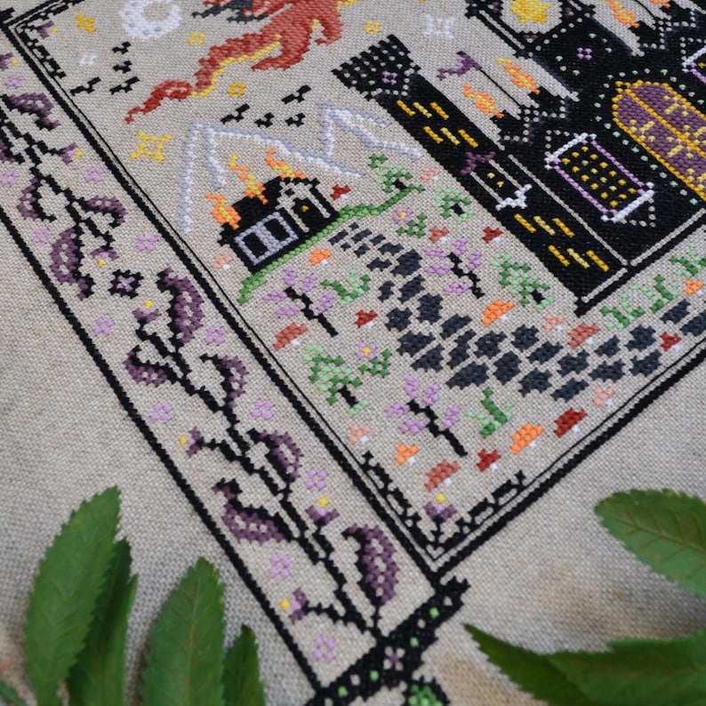 Castles & Dragons cross stitch pattern finish. Features flying fire dragon and a large castle on a scroll.